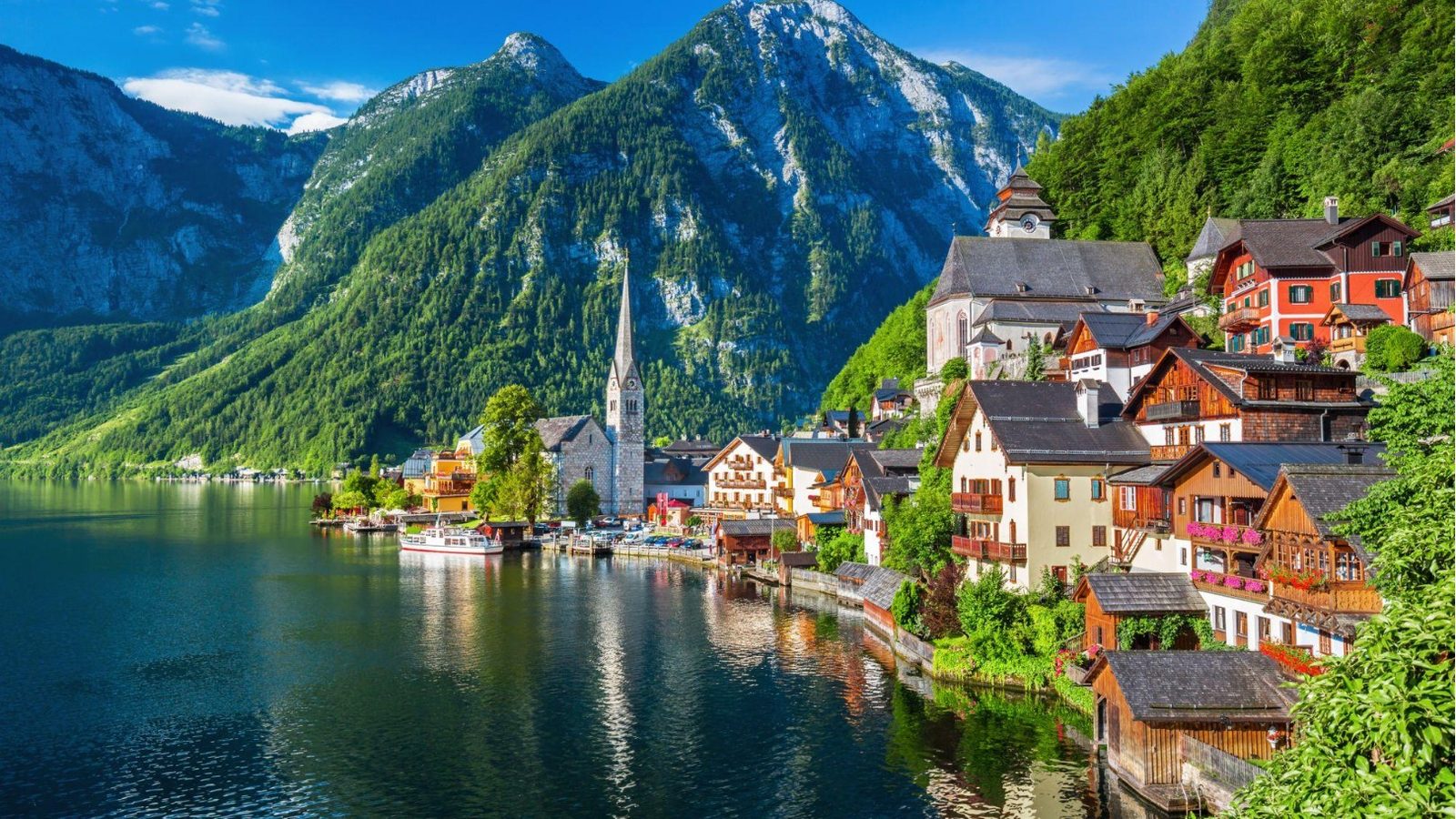 Auf dem Bild sieht man ein dorf am Wasser und im Hintergrund sieht man ein großes Gebirge